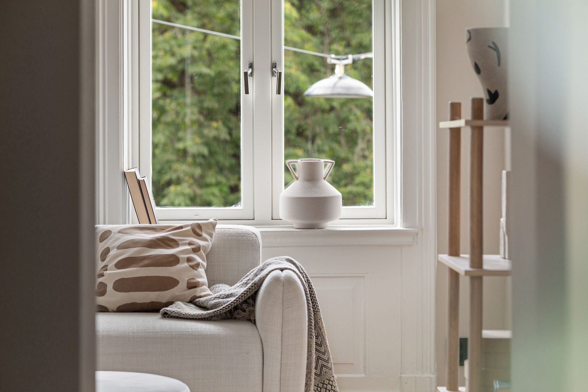Inviting living room with a comfortable sofa, soft blanket, and view through large windows.