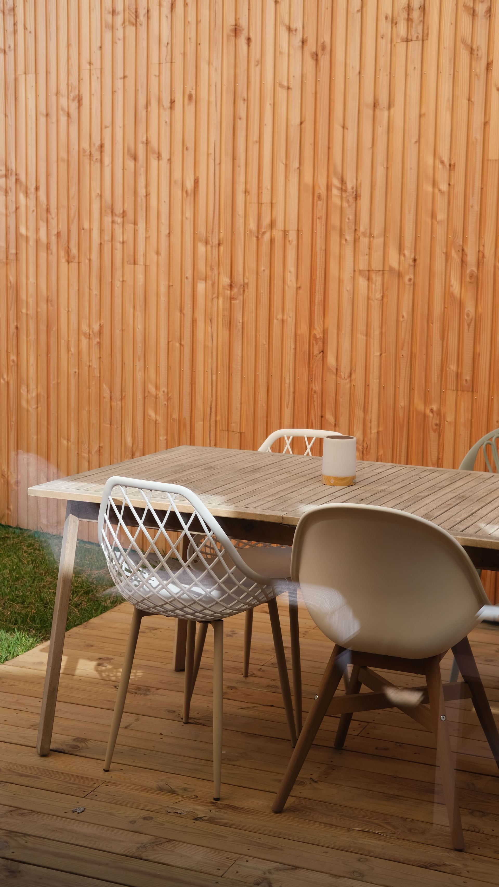 Stylish outdoor patio featuring a wooden table and chairs against a wooden fence.