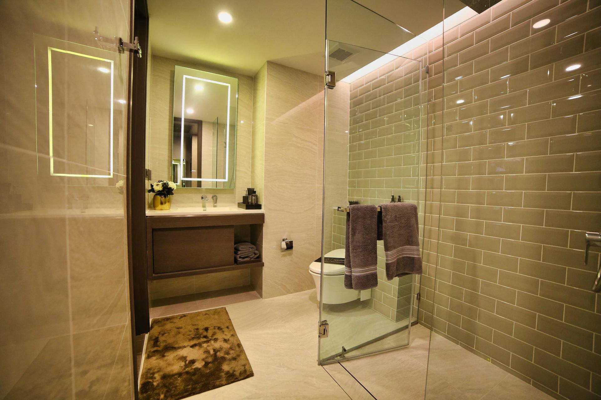 Spacious luxury bathroom featuring glass shower, illuminated mirrors, and sleek interior design.